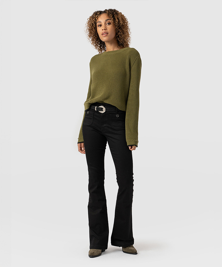 A model wearing black Saint and Sofia jeans with a green knitted jumper and green ankle boots.