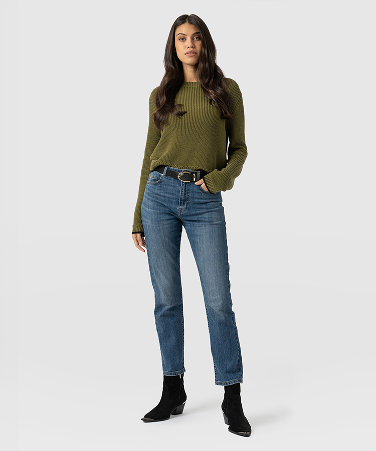 A model wearing Saint and Sofia jeans with a green knitted jumper and heeled black ankle boots.