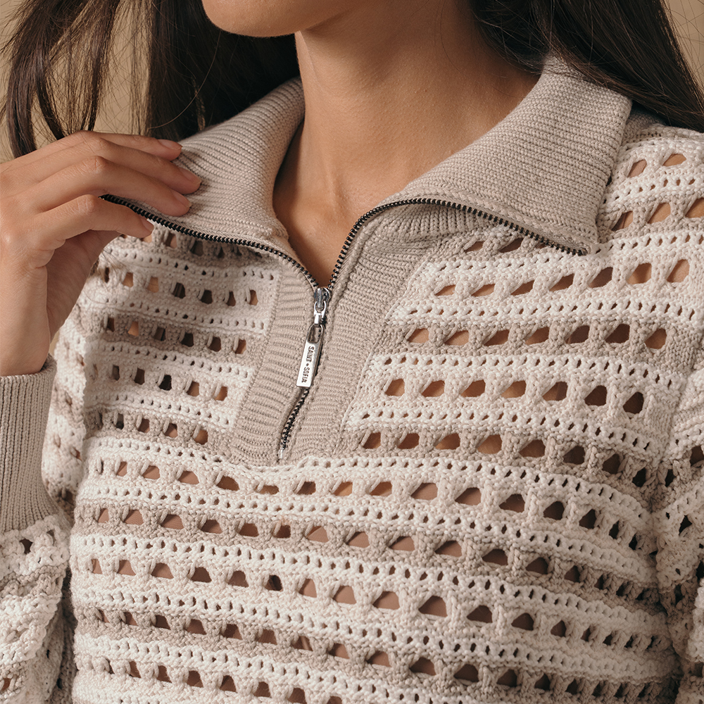 The Saint and Sofia Ester Quarter Zip top in beige and grey with openwork stitching.