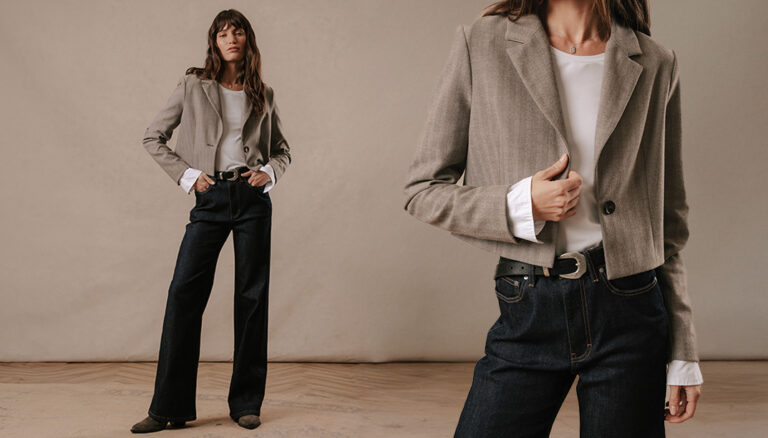 A model stood in a blue denim wide leg jeans wearing the Saint and Sofia Connie layering shirt with the Astrid cropped blazer
