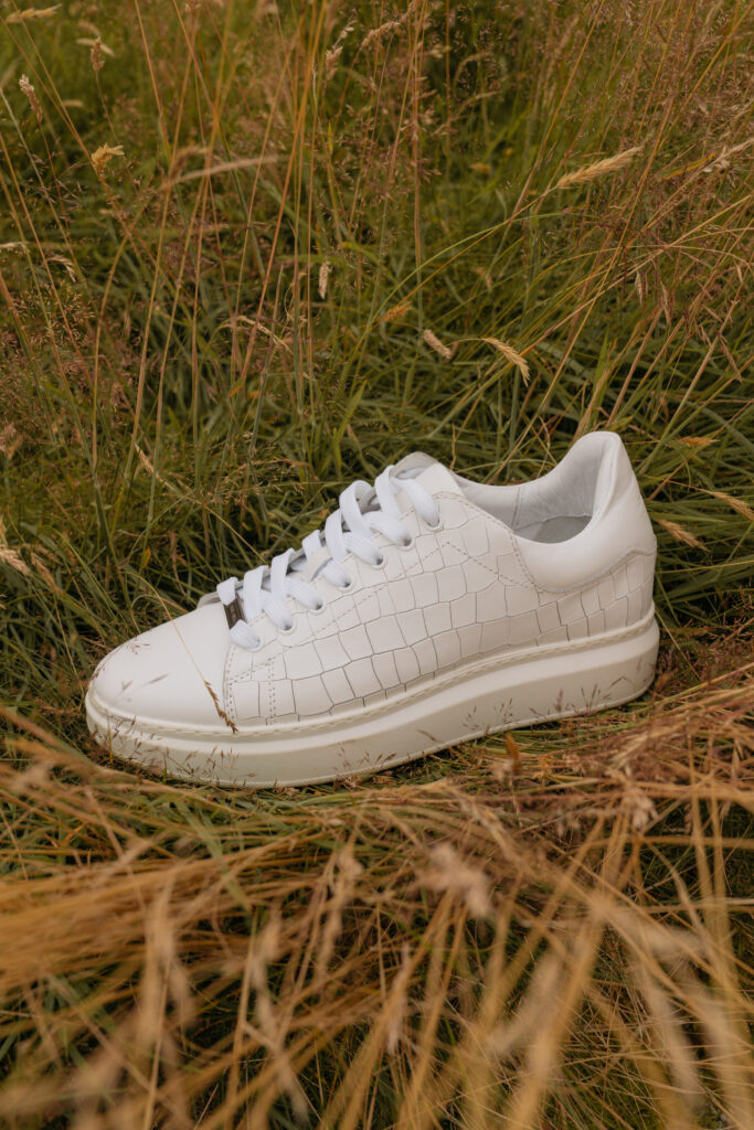White leather trainers with a croc-embossed finish and Saint and Sofia brand plaque at the lace.