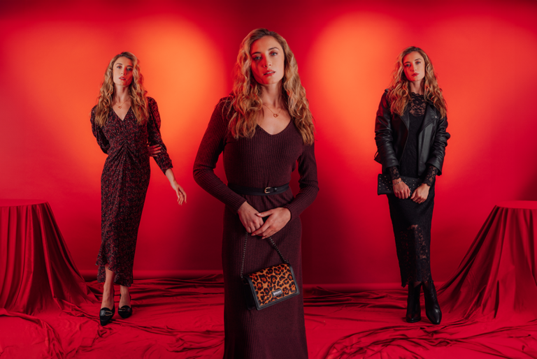 Three models stood in Saint and Sofia dresses. One wearing a V-neck midi with long sleeved and lightly puffed shoulders. One wearing a scoop neck knitted midi with long sleeves. And one wearing a black lace dress with a black leather jacket.