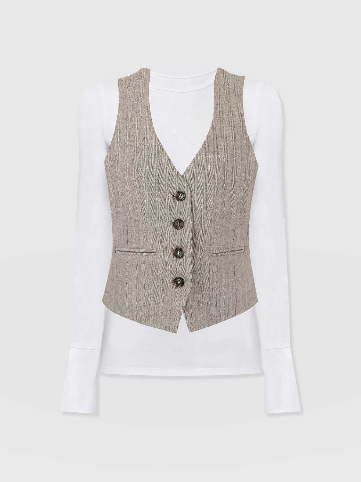 The Saint and Sofia Astrid Waistcoat in brown herringbone layered over the Connie Cuff Tee in white. A crew-neck slim-fit style with buttoned cuff sleeves that creates the illusion of a shirt when layered item other pieces.