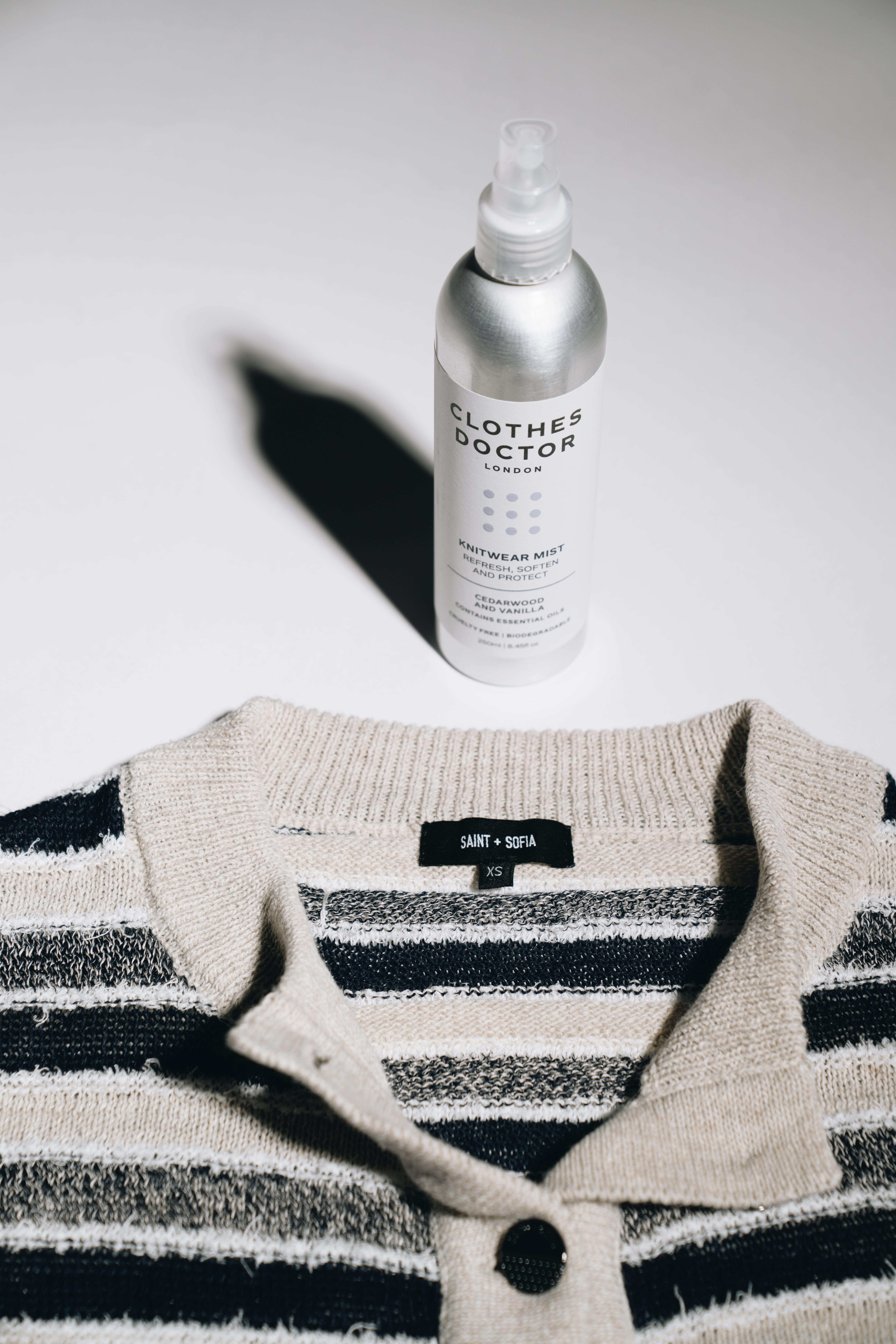 A Saint and Sofia striped cardigan beneath a bottle of knitwear care detergent by Clothes Doctor.