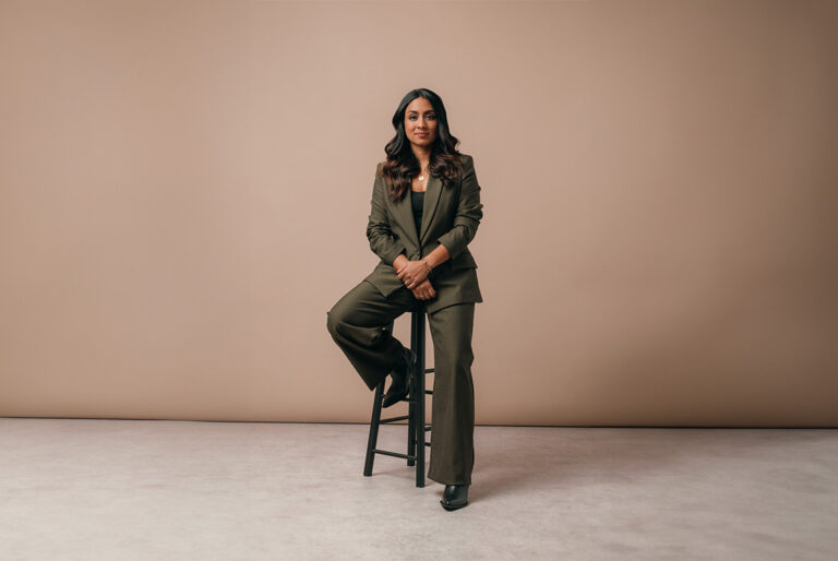BBC Sports Broadcaster Isa Guha sat on a stool wearing a green Saint and Sofia suit.