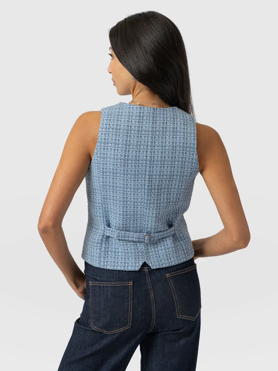 The Saint and Sofia Astrid Waistcoat in pale blue. A denim-effect textured design with gunmetal buttons down the front, a V-neckline, and a waist adjuster at the back.