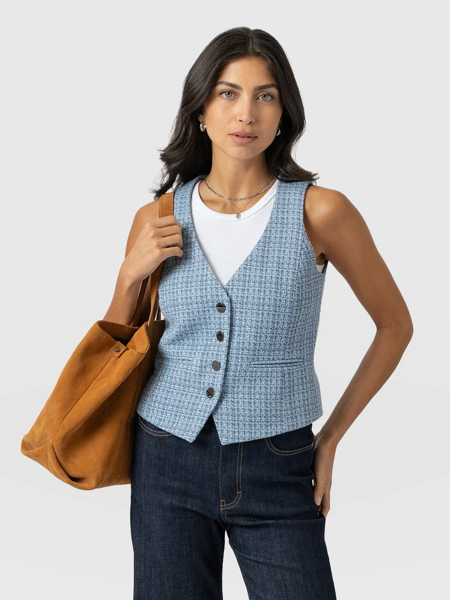 The Saint and Sofia Astrid Waistcoat in pale blue. A denim-effect textured design with gunmetal buttons down the front, a V-neckline, and a waist adjuster at the back.