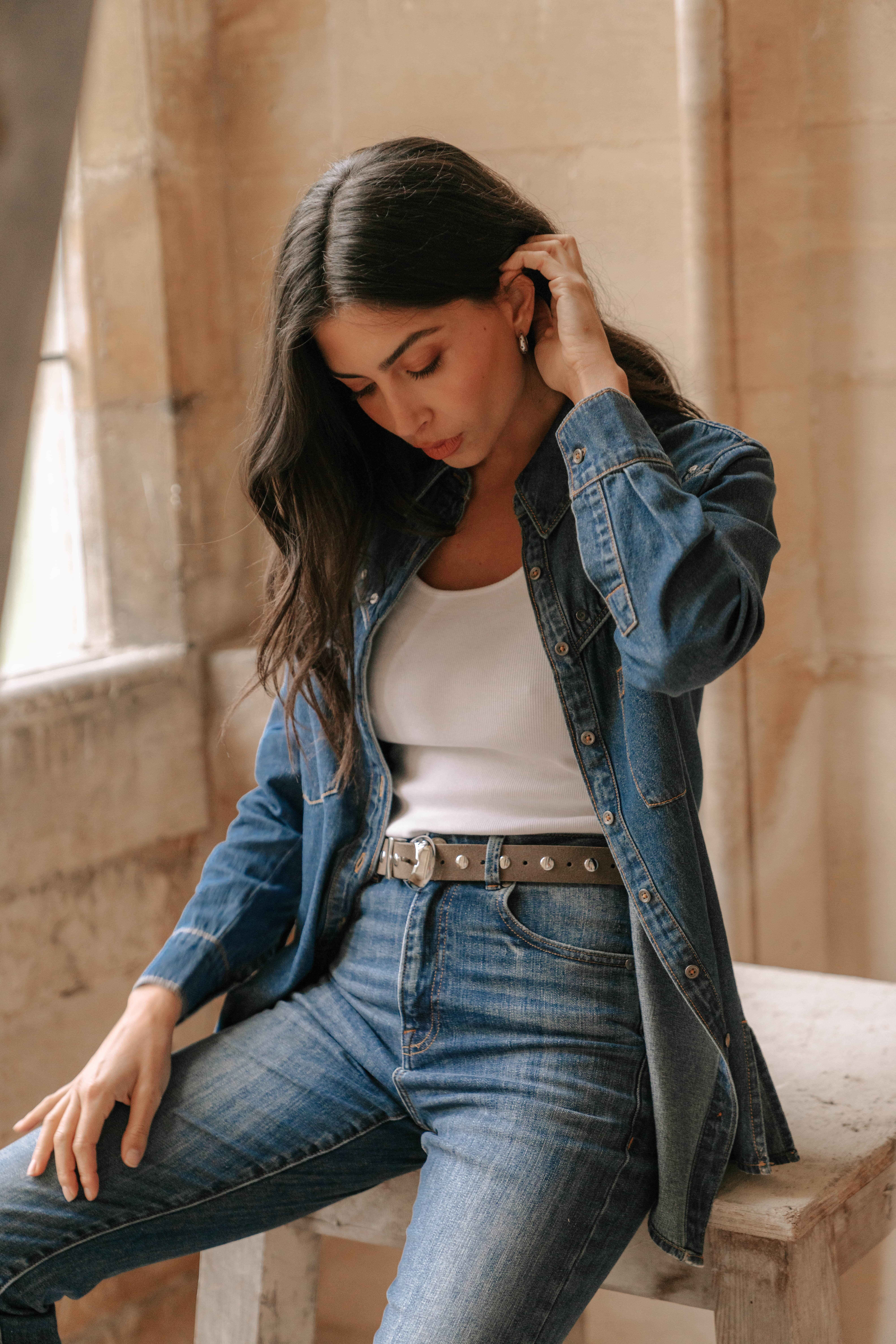 A model wearing the Sidney Denim Shirt with the Saint and Sofia Wide leg jeans for a double denim look. Worn over a white scoop neck vest.