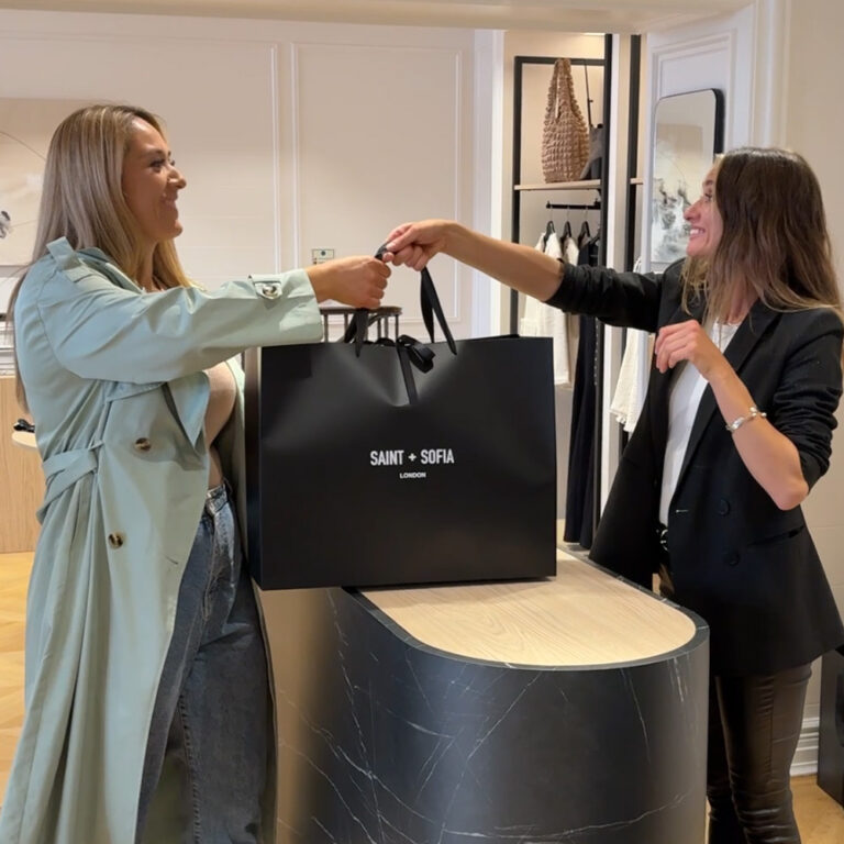 Amber, the Saint and Sofia personal stylist, handing over a bag to a happy customer with her handpicked outfit.