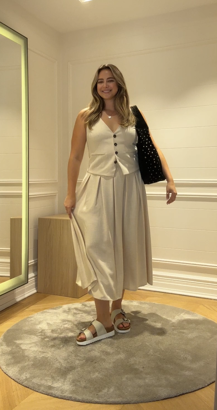 A size 14 model wearing the Saint and Sofia Eliza midi skirt. A cream linen effect design with pleats. It's styled with the matching waistcoat for a co-ord look.