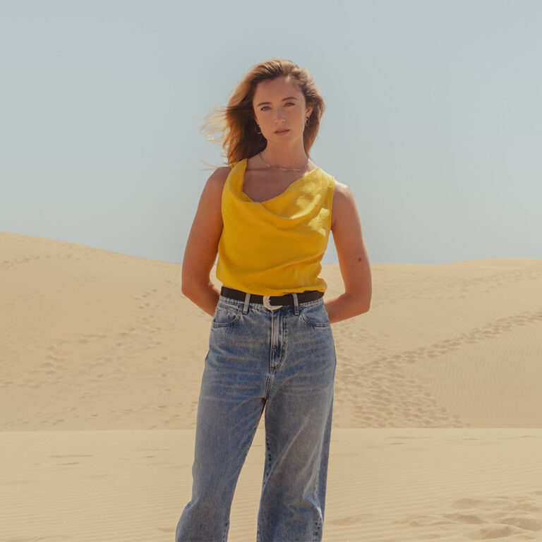 A model wearing a pair of the Saint and Sofia adjustable jeans with a yellow cowl neck top.