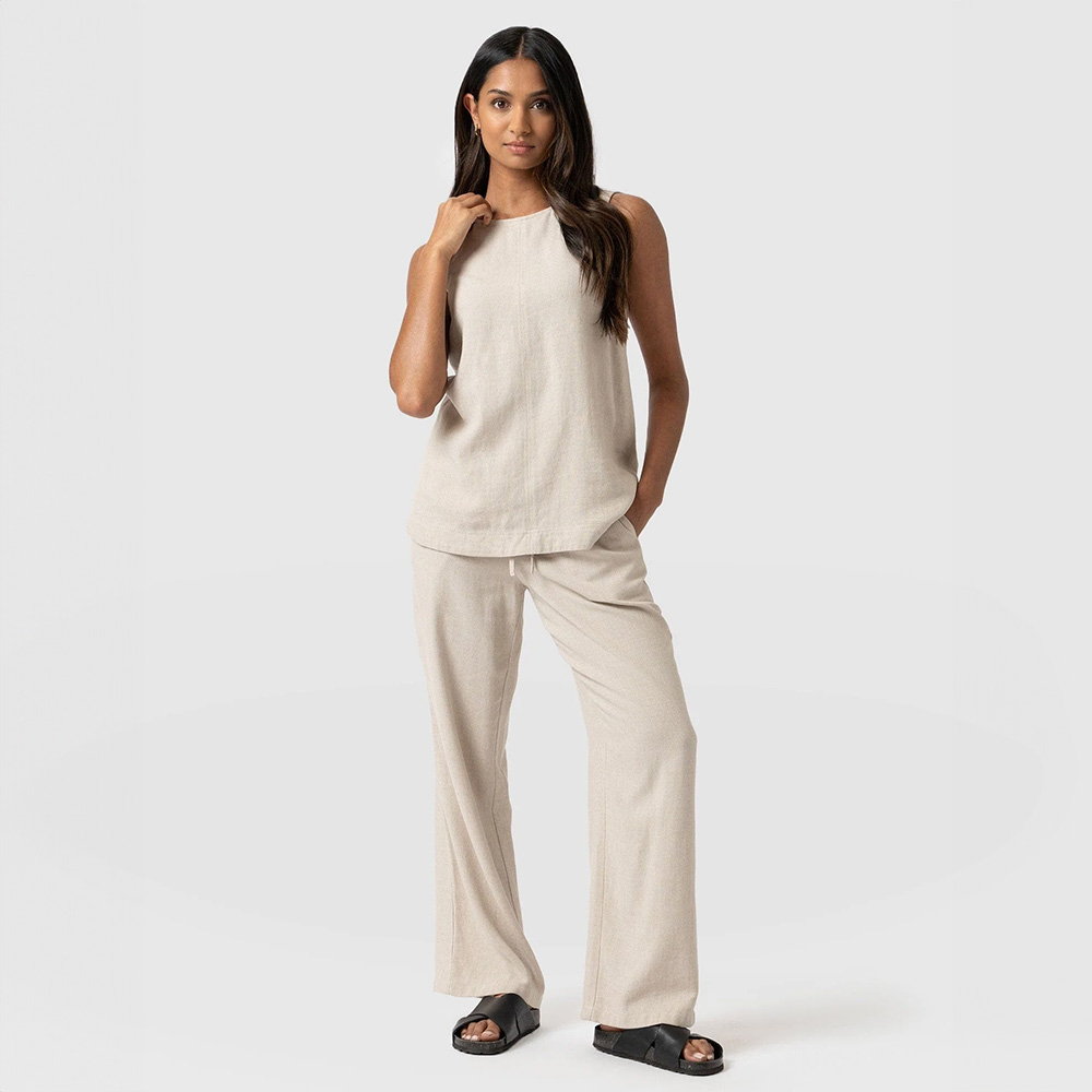 A model wearing the Corinne set by Saint and Sofia. A linen coord with wide leg trousers and a tunic-style top with a sleeveless design.