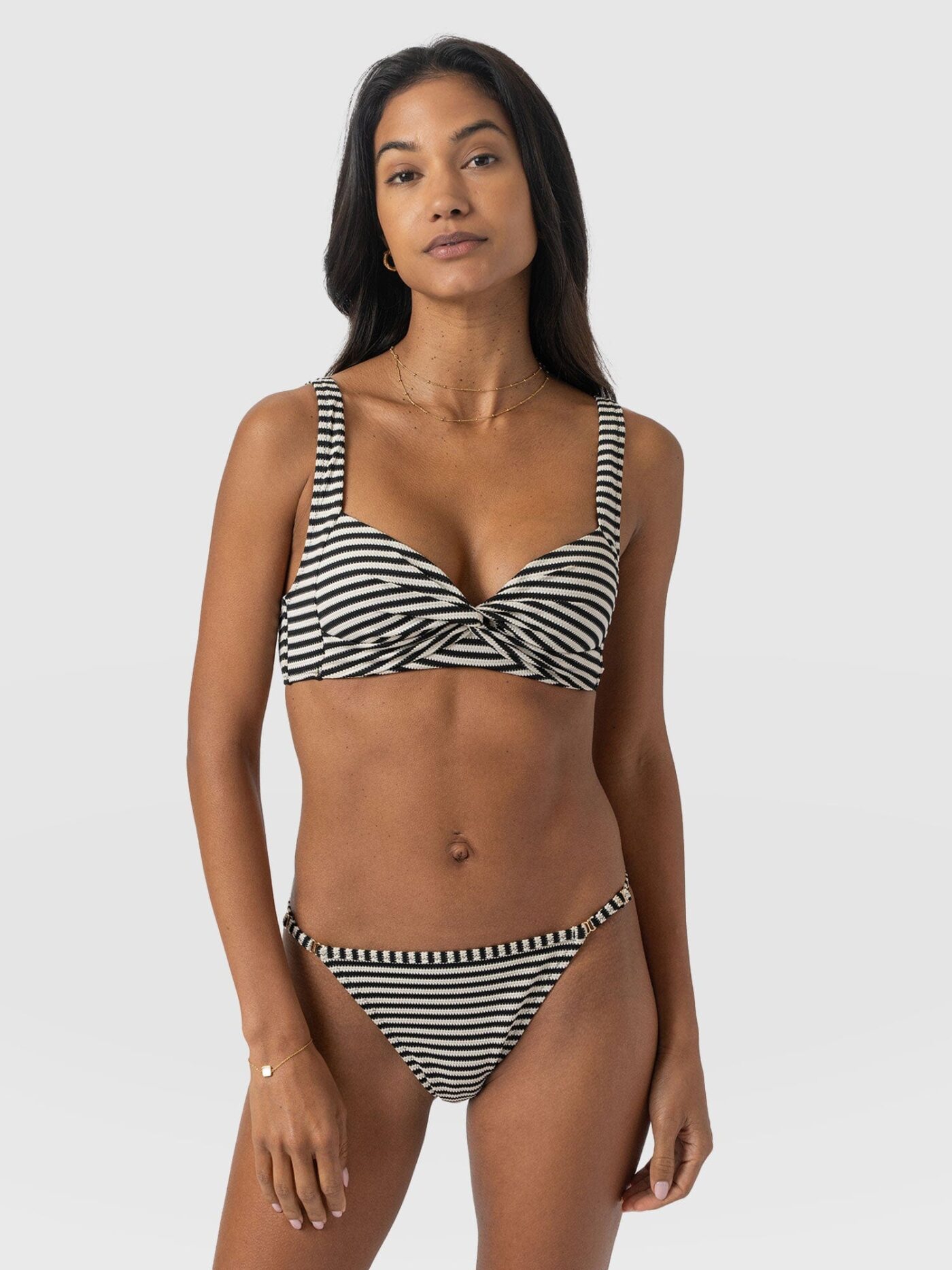 A model wearing a blue and white striped bikini with a twist front. From the Saint and Sofia holiday essentials collection.