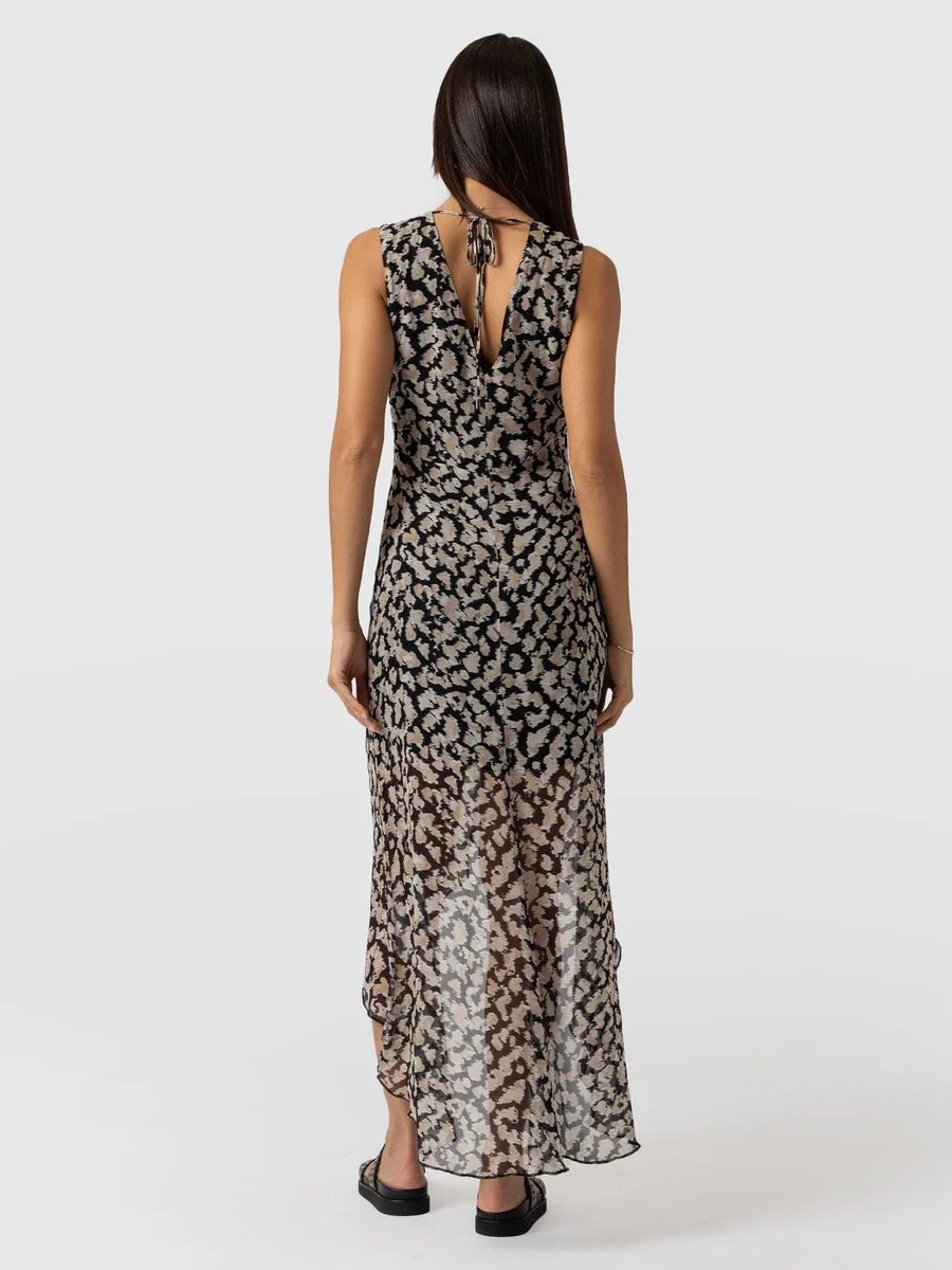 A model wearing the Saint and Sofia Lexi High Low Dress. A blurred floral design with an asymmetric hem and a V neckline. The perfect wedding guest dress.