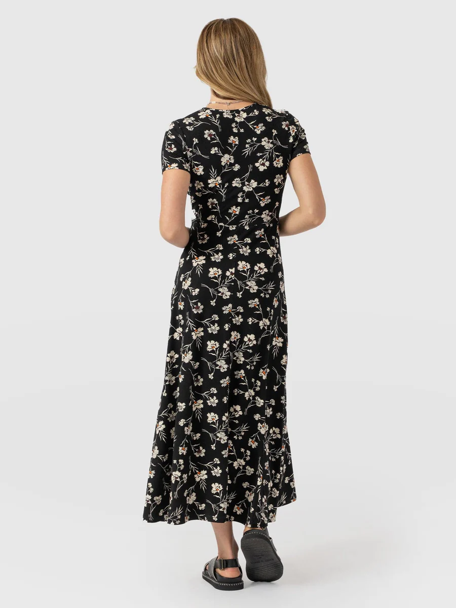 A model wearing the Saint and Sofia Maggie Wrap Dress with short sleeves. A floral wedding guest dress with a V neckline and midi length skirt.