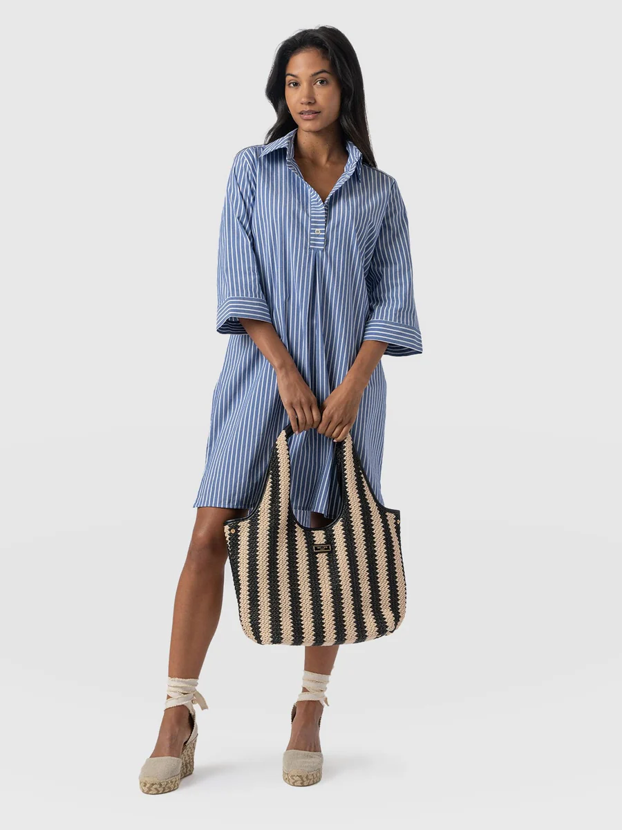 A model wearing the Saint and Sofia stevie dress. A shirt dress design with a relaxed silhouette, three-quarter length sleeves, collared neckline, and all-over striped print. The perfect summer mini dress.