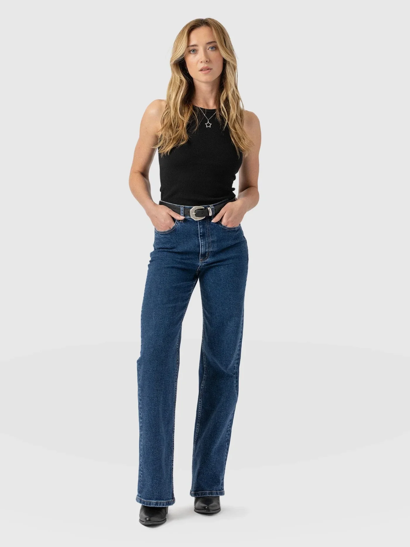 A model wearing a pair of Saint and Sofia Wide Leg Jeans in blue. This high waisted pair help to shorten the length of your torso.