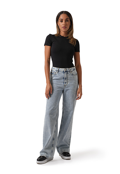 A model wearing the Saint + Sofia adjustable jeans in blue with a black short sleeve top.