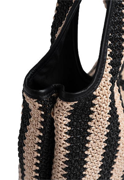 A close-up of the Saint + Sofia raffia bag where poppers have been added at the sides to allow you to shrink the shape of the silhouette if you are not using the bag to its full capacity.