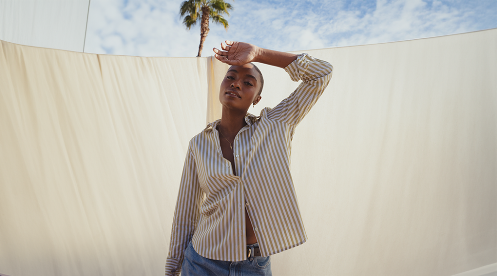 Model posing in striped green and white button up shirt.