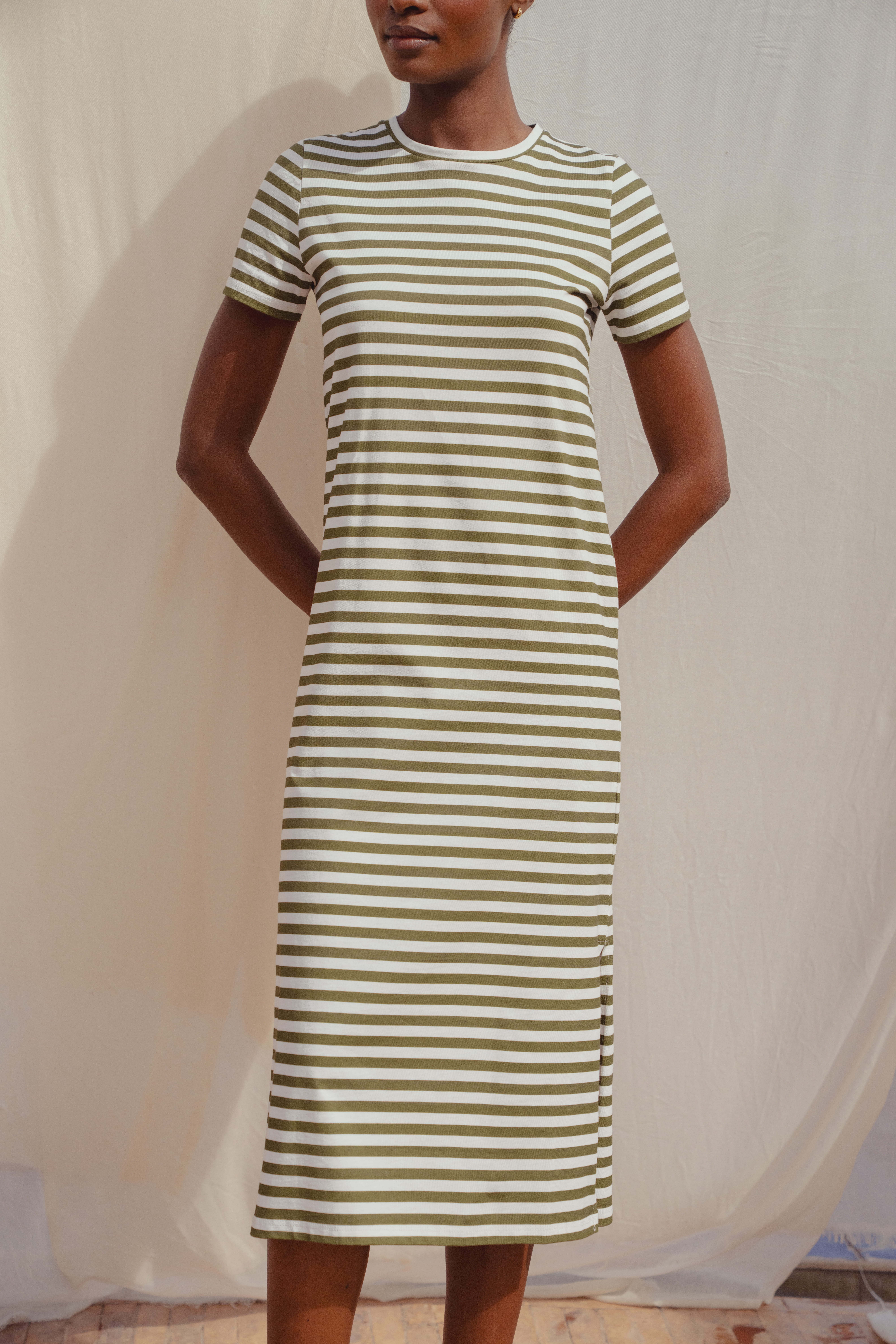 A close up shot of the Saint and Sofia Easy T Shirt Dress. A short sleeve, crew neck style with green and white stripes and a midi skirt length.