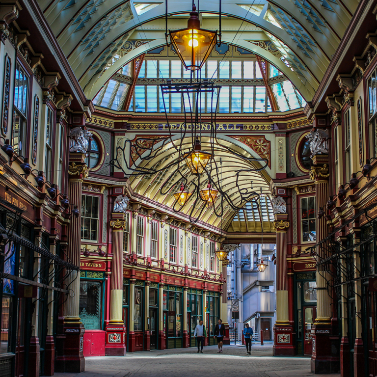 A picture of an empty Leadenhall Market in London, England. A grand shopping district with cobbled streets and a glass roof.